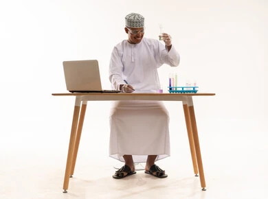 باحث عُماني يعمل على كمبيوتر محمول وقارورة مخبرية