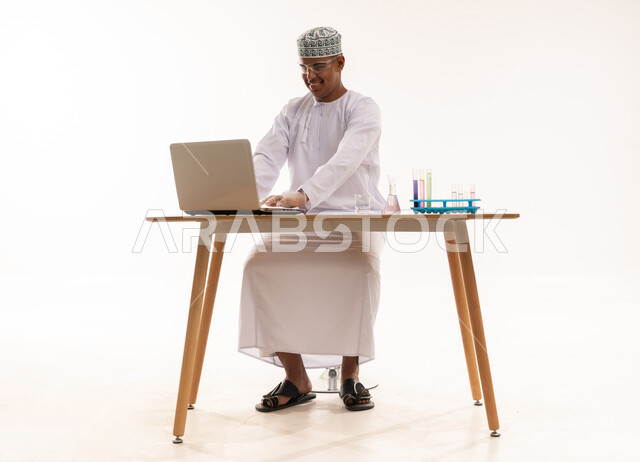 رجل عُماني مع كمبيوتر محمول وأدوات مختبرية