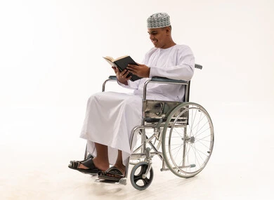 Omani Man in Wheelchair Reading Book on White Background