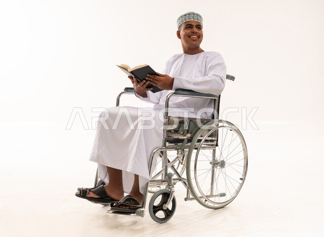 رجل عماني على كرسي متحرك يقرأ كتاباً