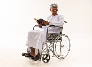رجل عماني على كرسي متحرك يقرأ كتاباً