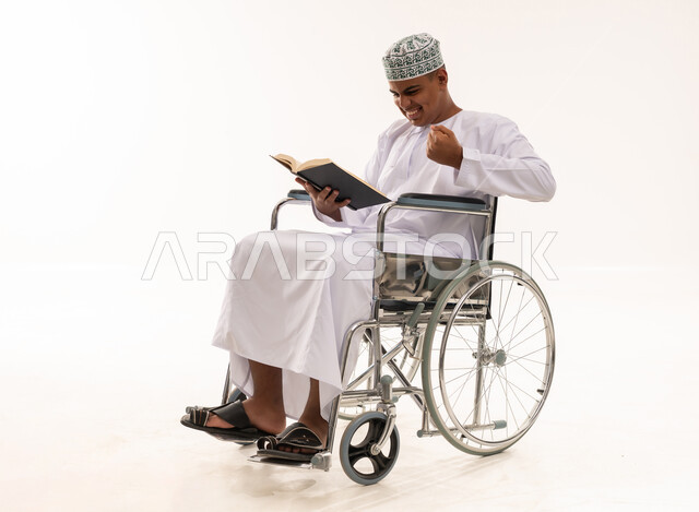 رجل عماني على كرسي متحرك يقرأ كتاباً