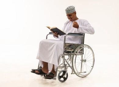 رجل عماني على كرسي متحرك يقرأ كتاباً