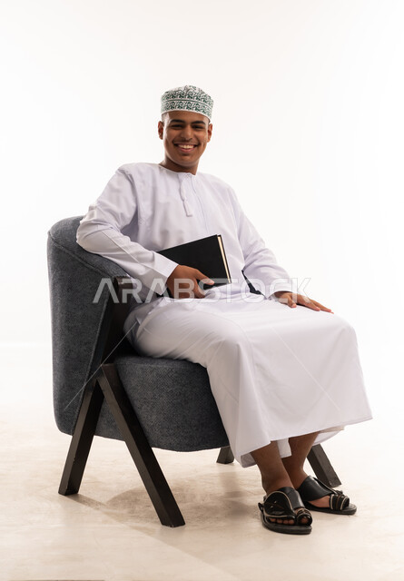 شاب عماني بالزي التقليدي يحمل دفتراً