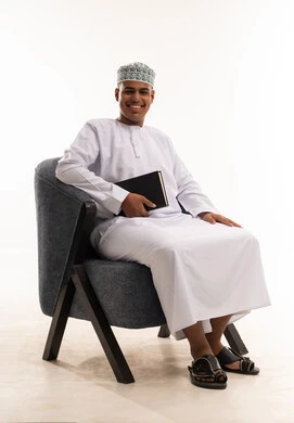 شاب عماني بالزي التقليدي يحمل دفتراً