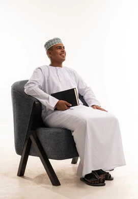 Omani Man in Traditional Dress Sitting with Book