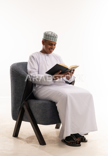رجل عماني يقرأ كتاباً بالدشداشة والكمة التقليدية