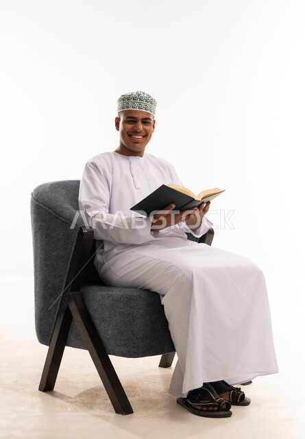 رجل عماني بالزي التقليدي يقرأ كتاباً