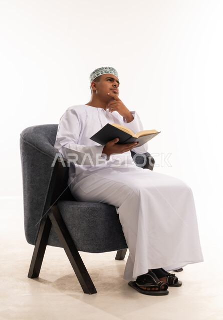 رجل عماني بالزي التقليدي يقرأ ويفكر