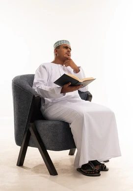 رجل عماني بالزي التقليدي يقرأ ويفكر