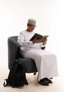 رجل عُماني بالزي التقليدي يقرأ كتاباً في الاستوديو