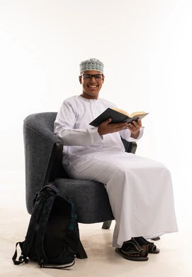 طالب عماني بالزي التقليدي يقرأ كتاباً