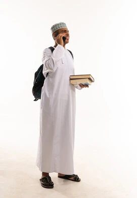 طالب عماني بالزي التقليدي يحمل كتباً وهاتف ذكي