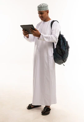 طالب عماني بالزي التقليدي يستخدم جهاز لوحي