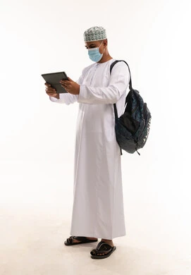 رجل عُماني بالزي التقليدي يستخدم جهاز لوحي رقمي