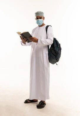 طالب عماني يقرأ كتاباً يرتدي الكمامة الطبية
