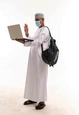 شاب عماني يستخدم الحاسوب المحمول مع كمامة طبية شاب عماني يستخدم الحاسوب المحمول مع كمامة طبية