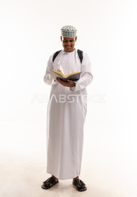 طالب عماني بالزي التقليدي يقرأ كتاباً