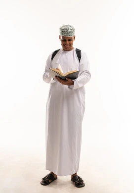 طالب عماني بالزي التقليدي يقرأ كتاباً