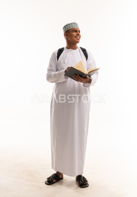 طالب عماني بالزي التقليدي يحمل كتاباً