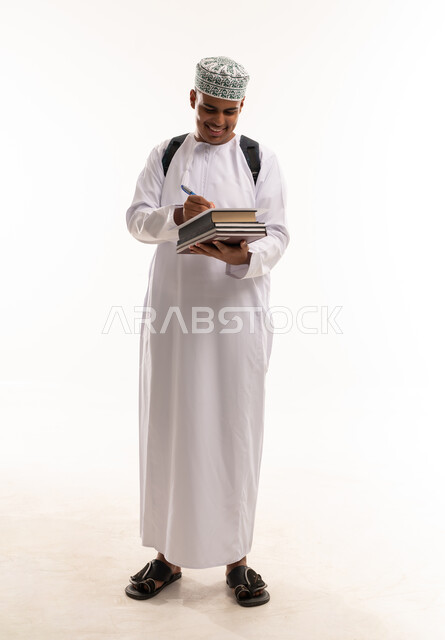 طالب عماني بالزي التقليدي يكتب ويحمل كتب
