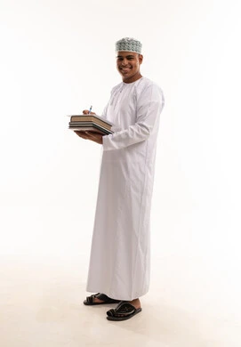 رجل عماني بالزي التقليدي يحمل كتباً