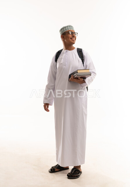طالب عماني بالزي التقليدي يحمل كتباً