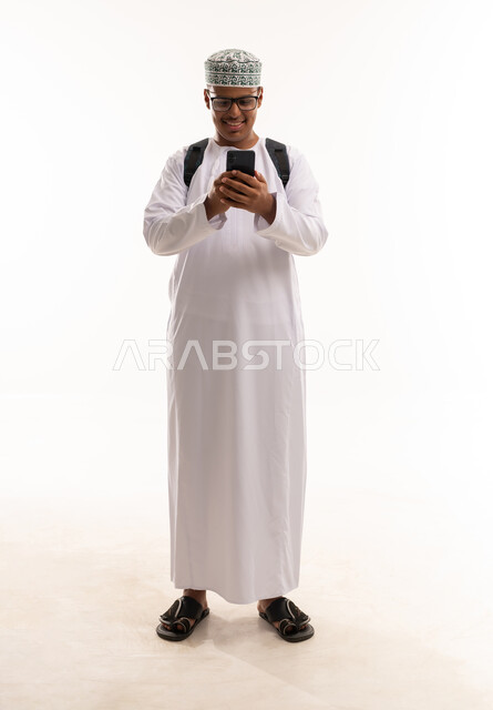 رجل عماني بالزي التقليدي يستخدم الهاتف الذكي