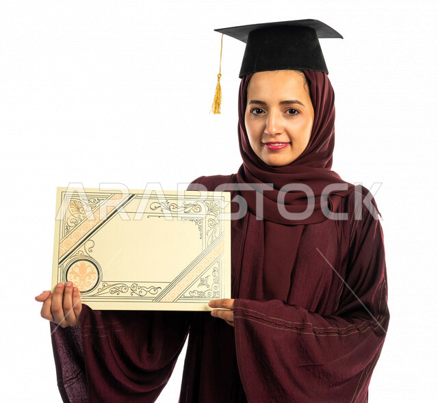 بورتريه طالبة جامعية خريجة عربية سعودية خليجية تلبس قبعة التخرج و تحمل شهادة تخرجها , ايماءات وجه ويدين تدل على السعادة بالتفوق والنجاح, حفل تخرج, نتائج الاختبارات, تلميذه متفوقه, مدارس وجامعات, التعليم في المملكة العربية السعودية , خلفية بيضاء .