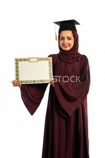 بورتريه طالبة جامعية خريجة عربية سعودية خليجية تلبس قبعة التخرج و تحمل شهادة تخرجها , ايماءات وجه ويدين تدل على السعادة بالتفوق والنجاح, حفل تخرج, نتائج الاختبارات, تلميذه متفوقه, مدارس وجامعات, التعليم في المملكة العربية السعودية , خلفية بيضاء .