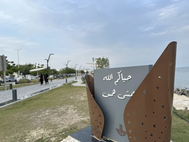 A modern walking experience, the entrance to the Hams walkway in the Eastern Province, Saudi Arabia, an open recreational destination, spaces for walking and relaxation, outdoor seating and benches, diverse restaurants and cafes, a calm family atmosphere.