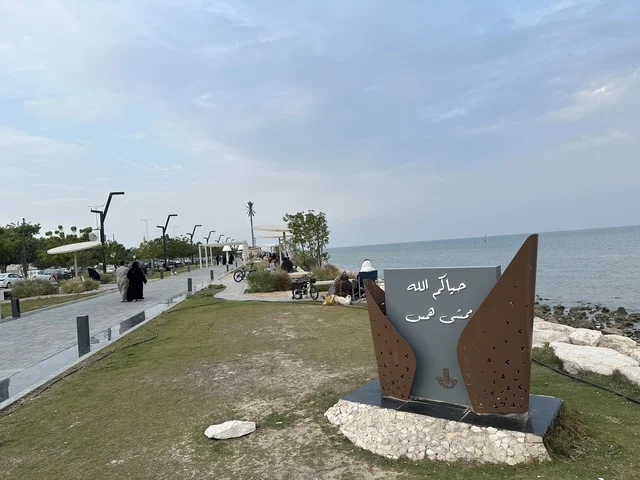 A modern walking experience, the entrance to the Hams walkway in the Eastern Province, Saudi Arabia, an open recreational destination, spaces for walking and relaxation, outdoor seating and benches, diverse restaurants and cafes, a calm family atmosphere.