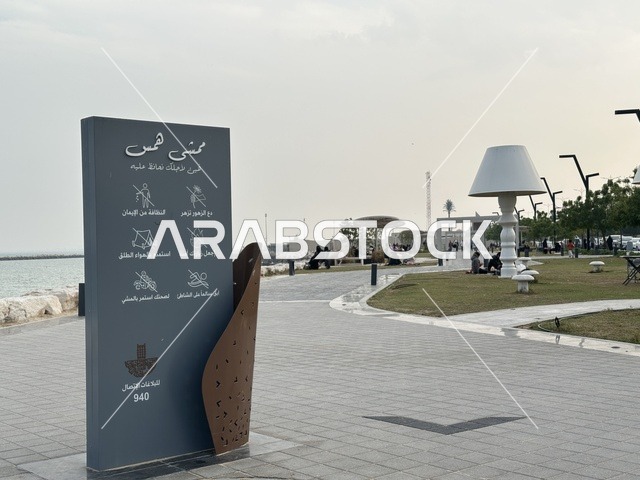A modern walking experience, the entrance to the Hams walkway in the Eastern Province, Saudi Arabia, an open recreational destination, spaces for walking and relaxation, outdoor seating and benches, diverse restaurants and cafes, a calm family atmosphere.