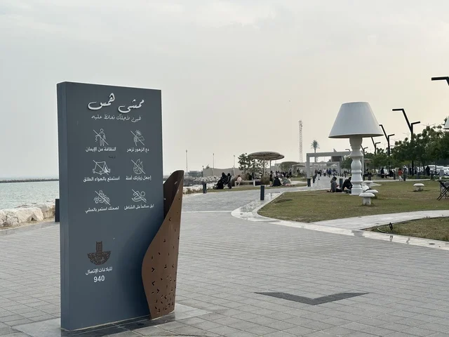 A modern walking experience, the entrance to the Hams walkway in the Eastern Province, Saudi Arabia, an open recreational destination, spaces for walking and relaxation, outdoor seating and benches, diverse restaurants and cafes, a calm family atmosphere.