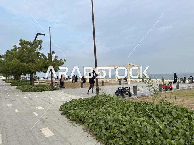 A calm family atmosphere, a modern walking experience, the Hams walkway in the Eastern Province, Saudi Arabia, an open entertainment destination, spaces for walking and relaxation, outdoor seating and benches, diverse restaurants and cafes.