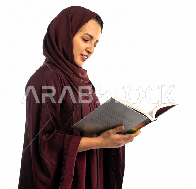 بورتريه طالبة جامعية عربية سعودية خليجية تحمل كتاب التخصص الجامعي , تخصص تصميم داخلي , تصفح وقراءة الكتب الجامعية , التعليم في جامعات المملكة العربية السعودية , خلفية بيضاء .