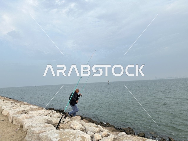 The skill of fishing at the Hams Walkway in the Eastern Province, Saudi Arabia, offers a calm family atmosphere, an open recreational destination, walking and relaxation spaces, a modern strolling experience, and outdoor seating and benches.