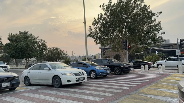 عبور المشاة والسيارات فى ممشى همس فى المنطقة الشرقية ليلاً، المملكة العربية السعودية ،أجواء عائلية هادئة ، تجربة تنزه عصرية،وجهة ترفيهية مفتوحة،  مساحات للمشي والاسترخاء ،  جلسات ومقاعد خارجية