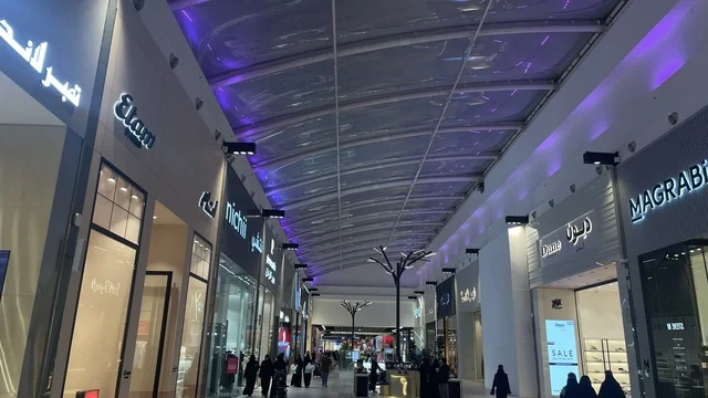 ممشى بسقف مقوس وشفاف يسمح بمرور الضوء، مركز تسوق في حي الأصالة شمال مدينة جدة في المملكة العربية السعودية سبتمبر 2025 ، تجربة تسوق ووجهة ترفيهية متكاملة للعائلة، تصميم عصري وماركات عالمية ومحلية