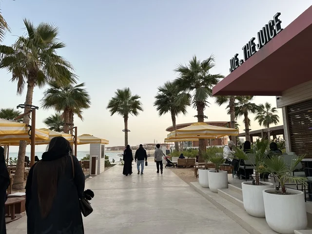 مظلات مخططة باللونين الأصفر والأبيض لتوفير الظل، سولت البحر وجهة ترفيهية وشاطئية عائلية تقع على طريق الكورنيش في الخبر في المملكة العربية السعودية، شاطئ رملي مع وجود مظلات وأشجار نخيل، تجديدات إضافية وتطويرات في 3  يناير 2026