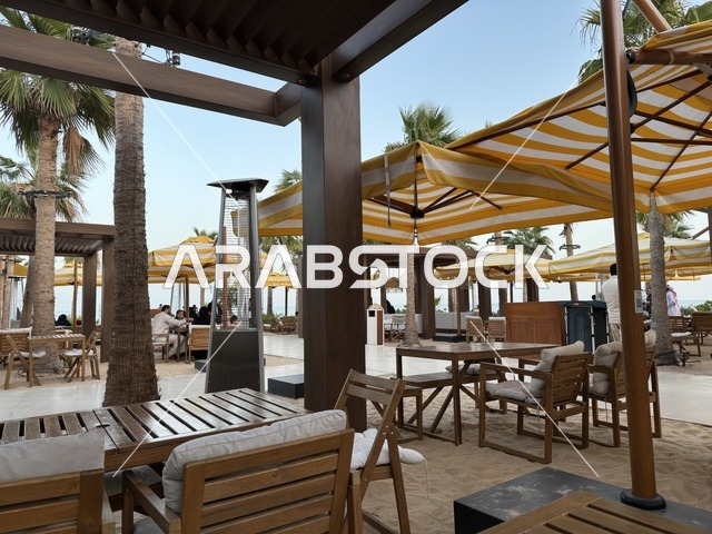 طاولات وكراسي خشبية مرتبة على رمل ناعم، سولت البحر وجهة ترفيهية وشاطئية عائلية تقع على طريق الكورنيش في الخبر في المملكة العربية السعودية، شاطئ رملي مع وجود مظلات وأشجار نخيل، تجديدات إضافية وتطويرات في 3  يناير 2026
