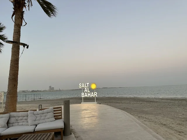 A sign for a tourist project or resort bearing the name of the place, "Soolat Al-Bahr" is a family-friendly recreational and beach destination located on the Corniche Road in Al Khobar, Saudi Arabia. Additional renovations and developments are set for January 3, 2026, featuring a sandy beach with umbrellas and palm trees.
