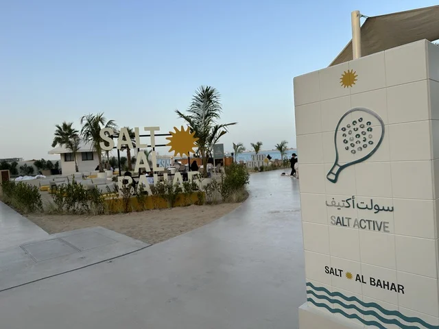 لافته تحمل رمز لمضرب رياضي، سولت البحر وجهة ترفيهية وشاطئية عائلية تقع على طريق الكورنيش في الخبر في المملكة العربية السعودية، تجديدات إضافية وتطويرات في 3  يناير 2026، شاطئ رملي مع وجود مظلات وأشجار نخيل