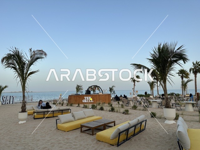 منطقة جلوس خارجية أرائك صفراء وطاولات خشبية، شاطئ رملي مع وجود مظلات وأشجار نخيل، سولت البحر وجهة ترفيهية وشاطئية عائلية تقع على طريق الكورنيش في الخبر في المملكة العربية السعودية، تجديدات إضافية وتطويرات في 3  يناير 2026