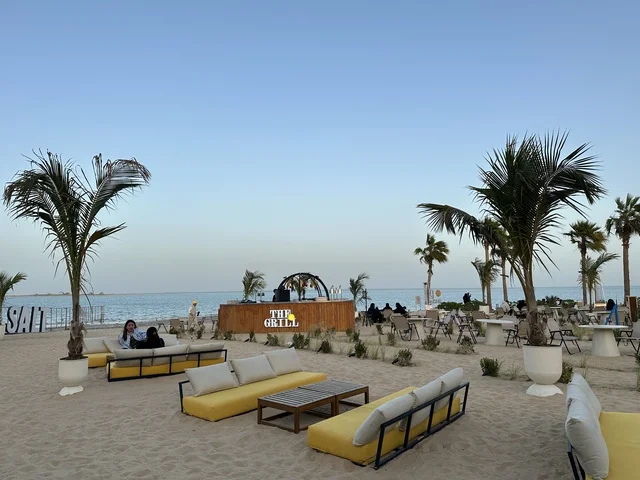 منطقة جلوس خارجية أرائك صفراء وطاولات خشبية، شاطئ رملي مع وجود مظلات وأشجار نخيل، سولت البحر وجهة ترفيهية وشاطئية عائلية تقع على طريق الكورنيش في الخبر في المملكة العربية السعودية، تجديدات إضافية وتطويرات في 3  يناير 2026