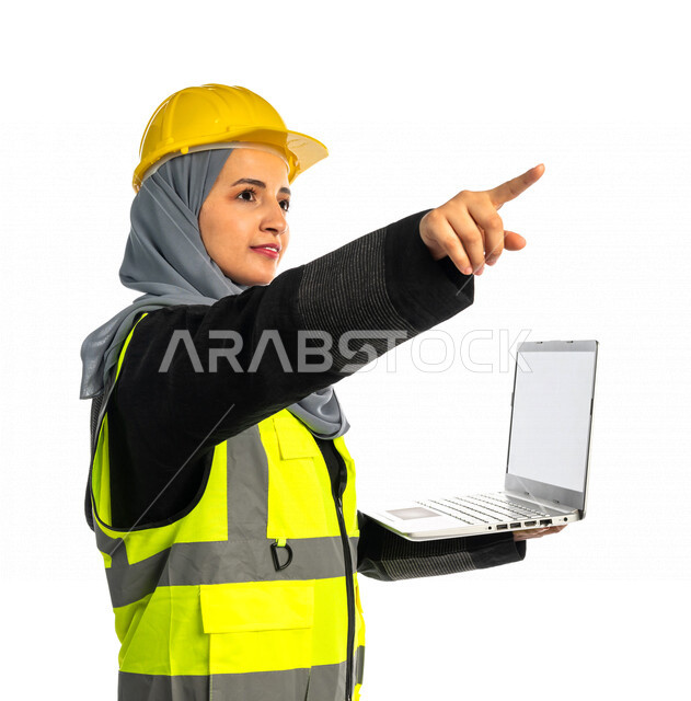 بورتريه مهندسة معمارية عربية سعودية خليجية تحمل بيدها جهاز اللابتوب المحمول ، مهندسة انشاءات محجبة ترتدي بدلة السلامة في العمل ، خوذة العمل ، لباس رسمي للعمل ، مشروع بناء ، خلفية بيضاء