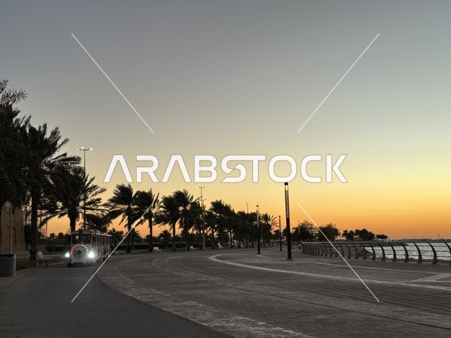 اشجار النخيل الخضراء، الواجهة البحرية في مدينة الدمام في وقت الغروب، منطقة حيوية ومتنفس رئيسي لسكان وزوار المنطقة الشرقية، كورنيش مطل على الخليج العربي في المملكة العربية السعودية