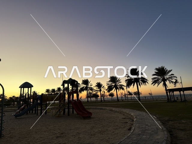 اشجار النخيل الخضراء، الواجهة البحرية في مدينة الدمام في وقت الغروب، منطقة حيوية ومتنفس رئيسي لسكان وزوار المنطقة الشرقية، كورنيش مطل على الخليج العربي في المملكة العربية السعودية