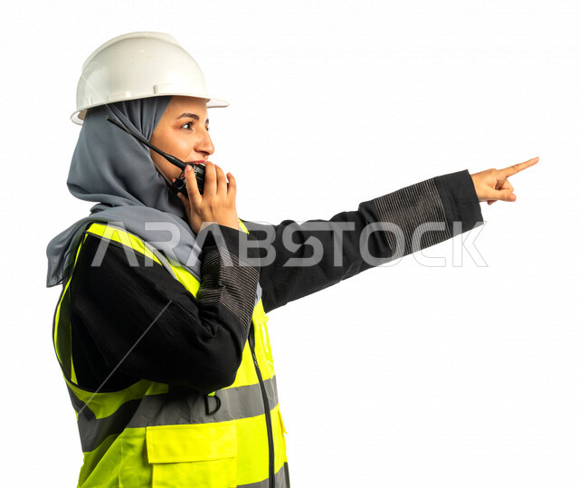 Portrait of a Saudi Arabian Gulf architect holding a wireless transceiver in her hand, a veiled construction engineer wearing a work safety suit, work helmet, work uniform, building project, white background
