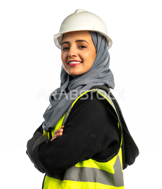 بورتريه مهندسة معمارية عربية سعودية خليجية مبتسمة و مكتفة اليدين ، مهندسة انشاءات محجبة ترتدي بدلة السلامة في العمل ، خوذة العمل ، لباس رسمي للعمل ، مشروع بناء ، خلفية بيضاء